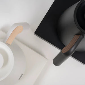 Detalizēts attēls melnai un baltai elektriskajai ūdenskannai ar koka detaļām baristas un filtrētās kafijas piederumiem no Timemore