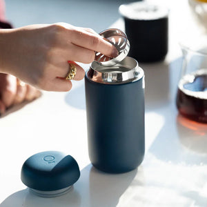 Roka, kas ieliek filtru matētā zilā atkārtoti lietojamā kafijas krūzē, daļa no Take away un EspressoGear, viss par kafiju.